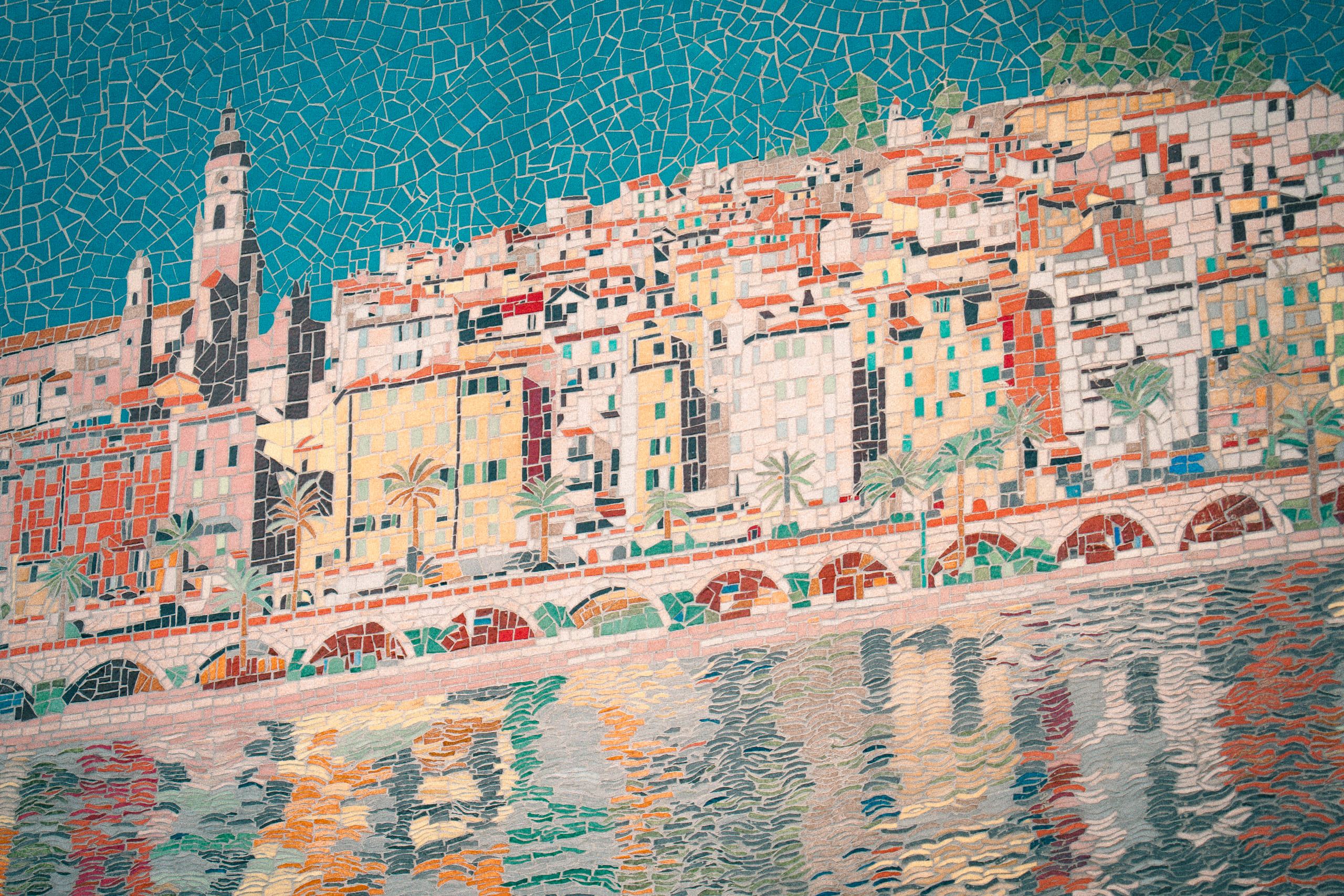 A tiled mosaic of a Riviera old town — pastel houses stacked under terracotta roofs, an arcaded quay and palms, reflected in the harbour water below.